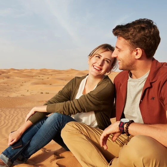 Couple relaxing together on golden sand dunes during an Abu Dhabi desert safari