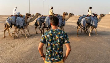 Visitor watching camels at Al Wathba camel track during a morning 4x4 tour from Abu Dhabi
