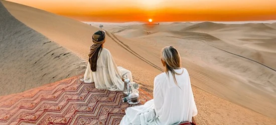 Two travellers in light clothing at a sunrise desert setup