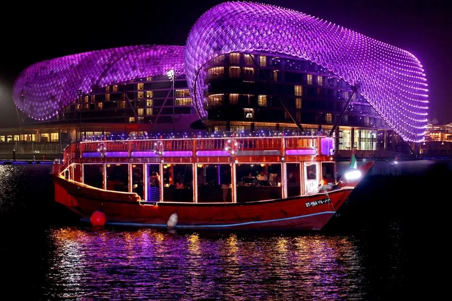 The stunning wooden double decker dhow standing anchored facing the stunning architecture