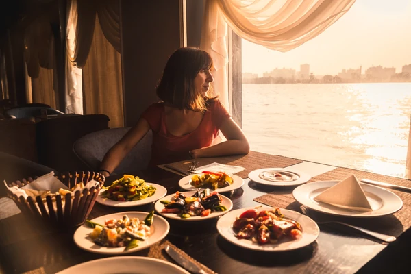 Guests enjoying midday buffet on Abu Dhabi dhow lunch cruise with Yas Island skyline