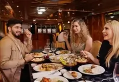 Group of friends dining aboard an dhow cruise dinner in Abu Dhabi, enjoying an evening meal with skyline views  (Credit: Abu Dhabi tourism )