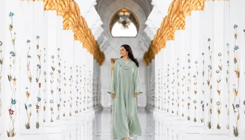 Visitor walking through the floral marble columns of Sheikh Zayed Grand Mosque in Abu Dhabi