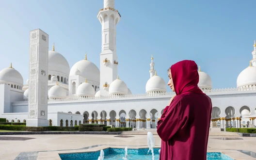 Visitor wearing modest clothing outside Sheikh Zayed Grand Mosque in Abu Dhabi