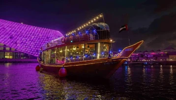 Traditional dhow cruise illuminated at night in Abu Dhabi