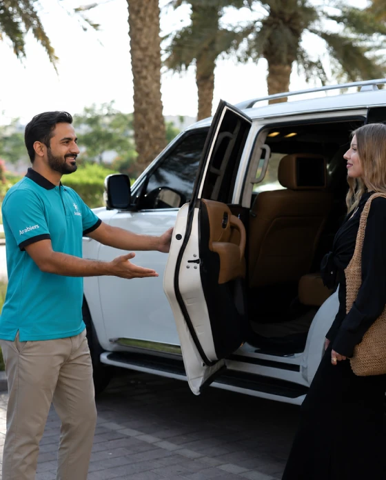 Arabiers private tour guide welcoming a couple beside a luxury SUV in Abu Dhabi