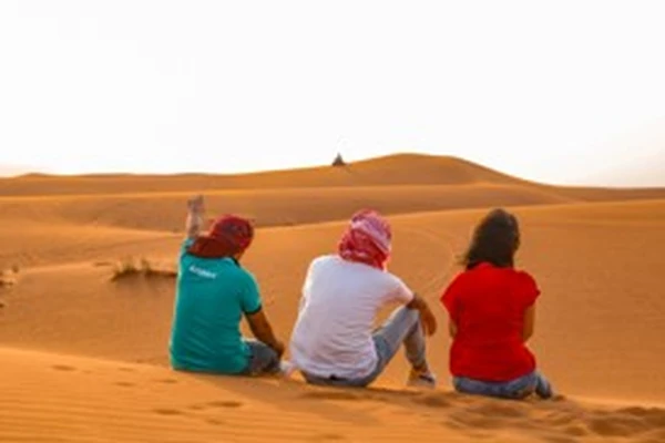 Guests watching the sunset over Dubai desert dunes on an Arabiers evening safari tour
