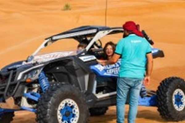 Arabiers Holidays guide with a guest beside a dune buggy in the Dubai desert