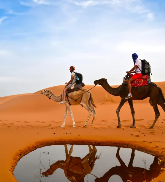 Tourists riding camels during desert trekking experience in Arabian desert
