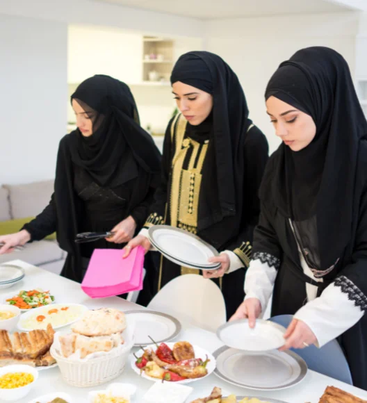 Emirati women preparing and serving traditional food at dining table