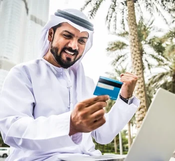 Traveller applying online for a Dubai tourist visa with payment card and laptop, visa guide by Martin Muthugumi for Arabiers