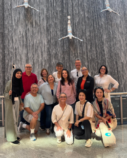 Khadija Nasir leading an Arabiers Holidays tour group at the waterfall inside the Dubai Mall, holding a tour guide flag