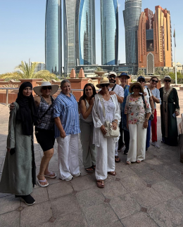 Khadija Nasir with an Arabiers Holidays tour group at Emirates Palace, Abu Dhabi, the Etihad Towers skyline behind them