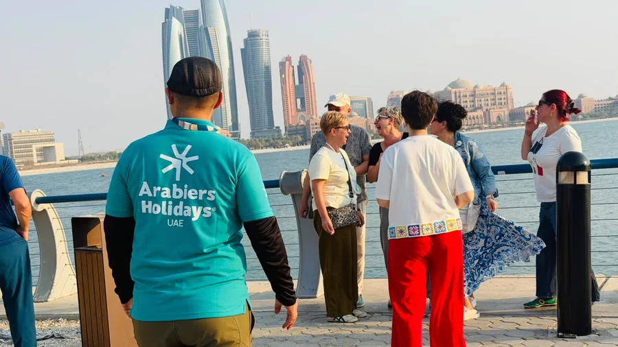 Khurshed Kamalov of Arabiers Holidays guiding guests on the Abu Dhabi Corniche with Etihad Towers and Emirates Palace behind