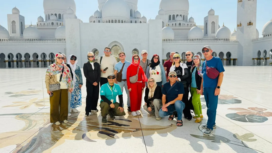 Khurshed Kamalov with an Arabiers Holidays tour group of sixteen guests posing in the courtyard of Sheikh Zayed Grand Mosque