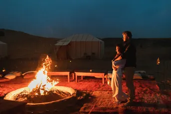 Couple beside a bonfire at an overnight desert camp in Abu Dhabi, a private camping experience overseen by Mujeeb Rahman for Arabiers Holidays