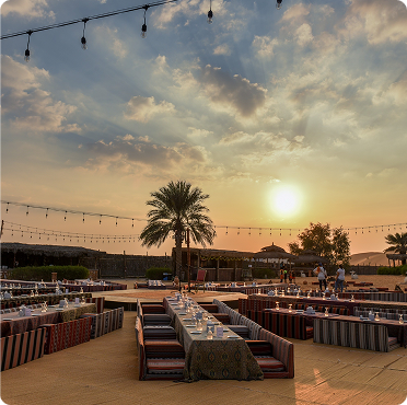 Luxury desert camp wedding reception setup in Abu Dhabi with majlis seating and sunset dining under open sky