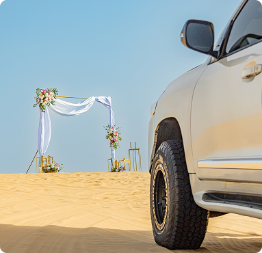 TLuxury SUV parked at a private desert wedding venue in Dubai with floral ceremony arch on golden sand dunes