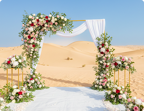 Floral wedding arch at private desert wedding venue in Dubai set against golden sand dunes