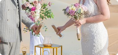 Bride and groom performing sand ceremony ritual at private desert wedding venue in Dubai with floral décor