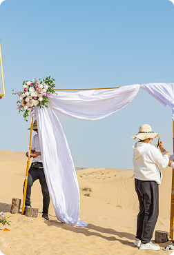 Wedding team setting up floral ceremony arch in a private desert wedding venue in Dubai sand dunes