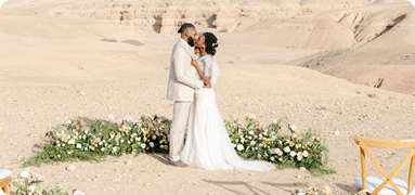 Bride and groom exchanging vows in a private desert wedding venue in Dubai with floral ceremony setup on sand dunes