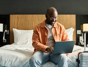 Traveller comparing hotel rates online from a hotel room with luggage for Arabiers UAE booking support
