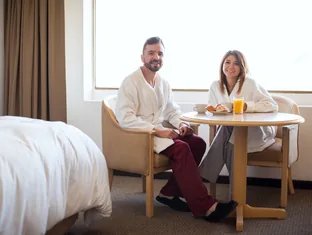 Couple having breakfast in a hotel room while reviewing room and meal plan details with Arabiers UAE