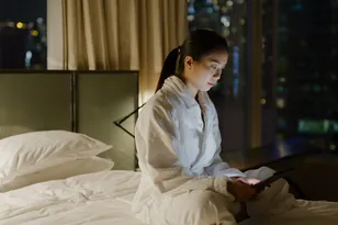 Traveller reviewing a hotel booking on a tablet at night, selected by Arabiers to explain international hotel booking support from the UAE