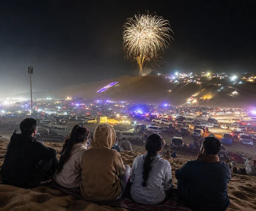 Visitors watching fireworks and off-road vehicles at the Liwa Moreeb Dune Festival in the Abu Dhabi desert