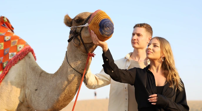 Couple posing beside a camel during an Abu Dhabi camel riding experience