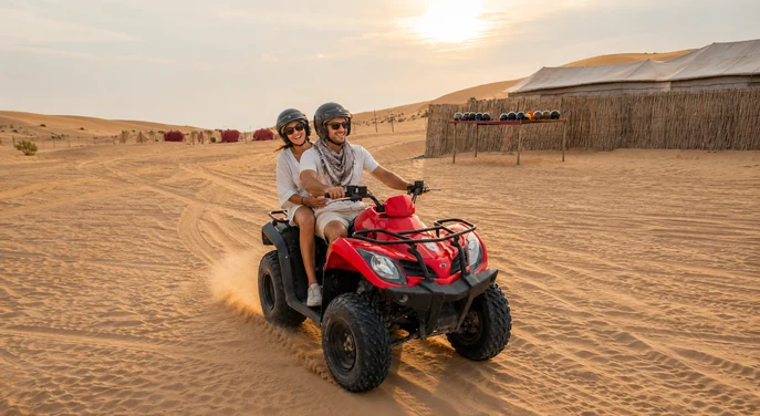 Couple riding a quad bike beside an Abu Dhabi desert camp