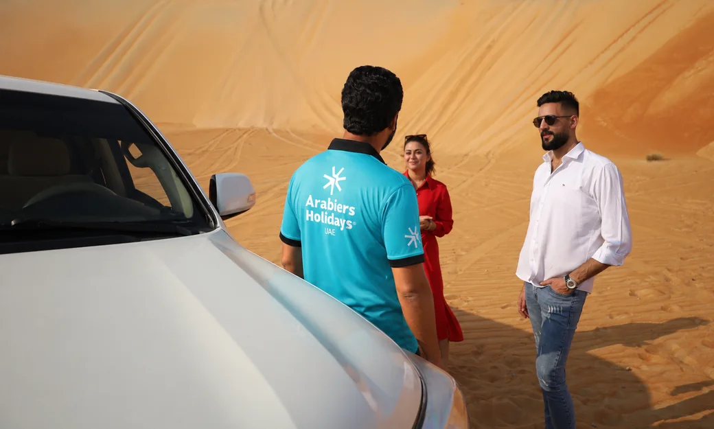 Arabiers desert safari guide welcoming guests beside a 4x4 in Abu Dhabi