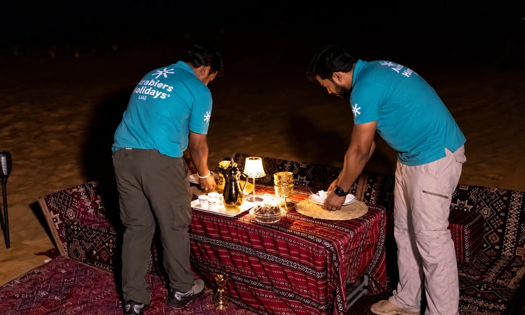 Arabiers staff arranging a private dining table at the Al Quaa desert camp