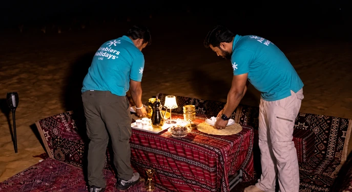 Arabiers staff arranging a private dining table at the Al Quaa desert camp