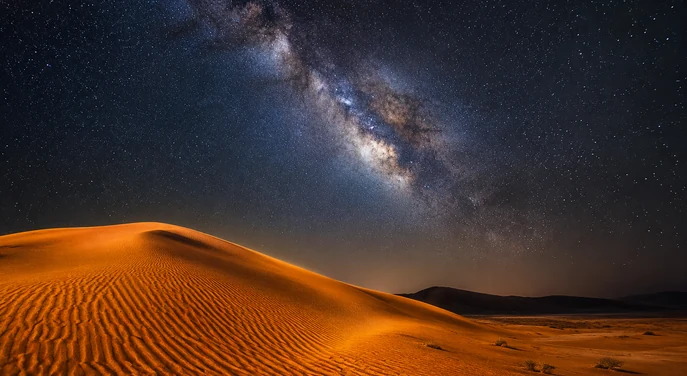 Milky Way stretching above illuminated dunes at Al Quaa desert