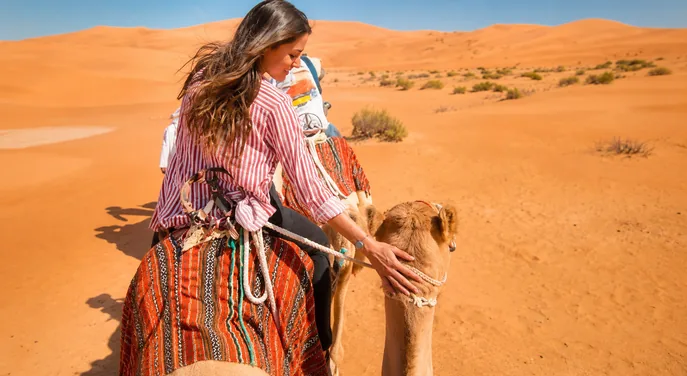 Guest enjoying a traditional camel ride across the Abu Dhabi desert dunes