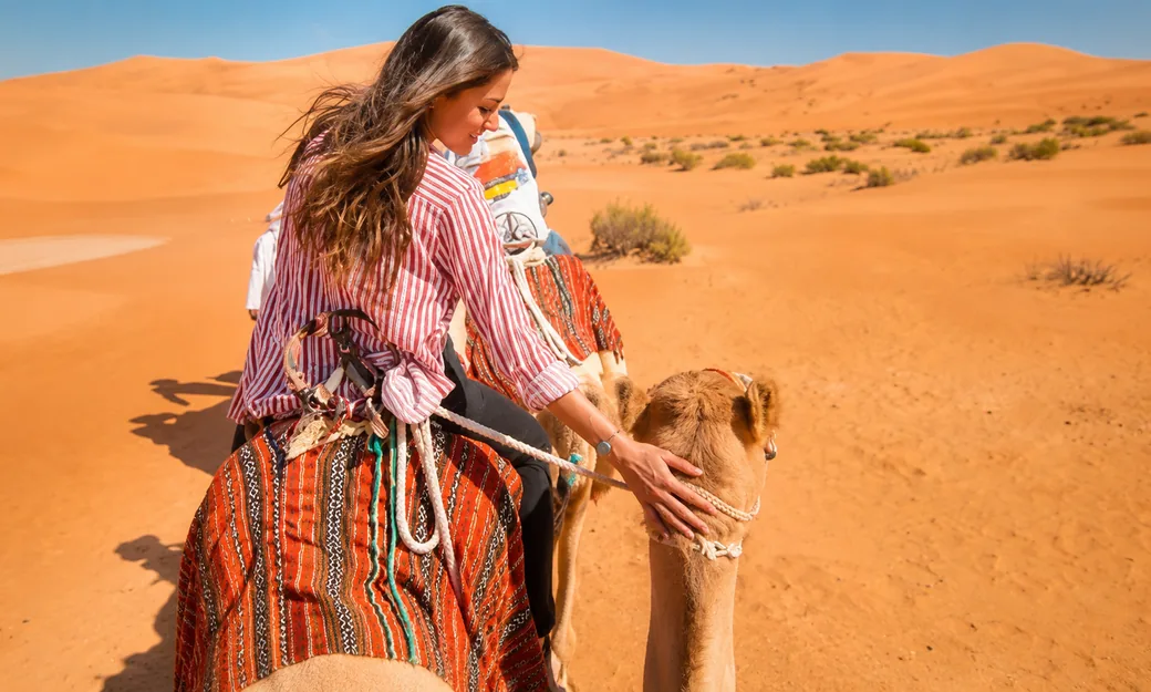 Guest enjoying a traditional camel ride across the Abu Dhabi desert dunes