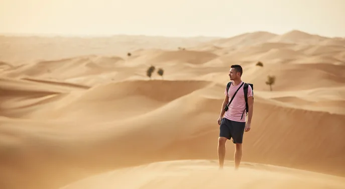 Guests walking with a Bedouin guide across the open Abu Dhabi desert