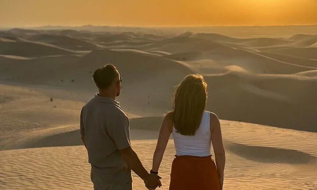 Couple holding hands while watching the sunset over the Abu Dhabi desert