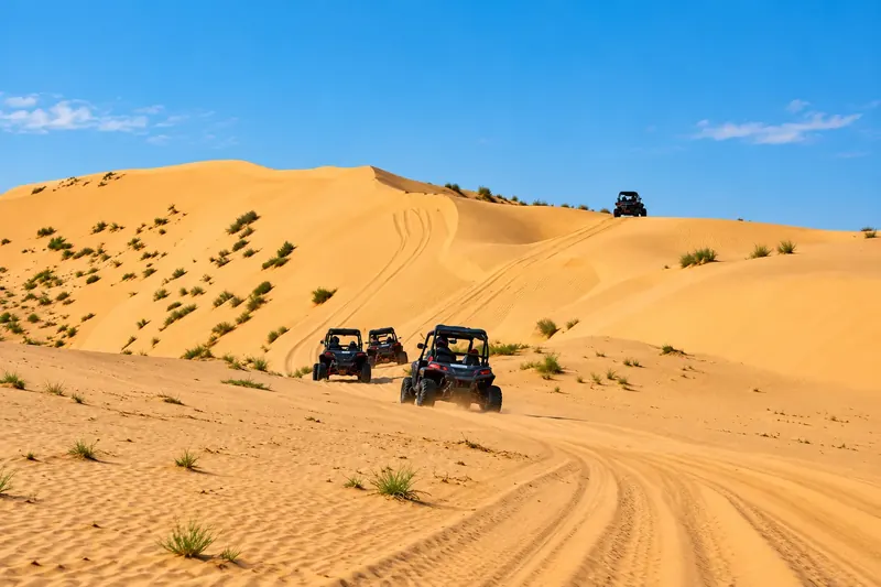 A convoy of dune buggies climbing a large sand dune in the Al Khatim desert, Abu Dhabi