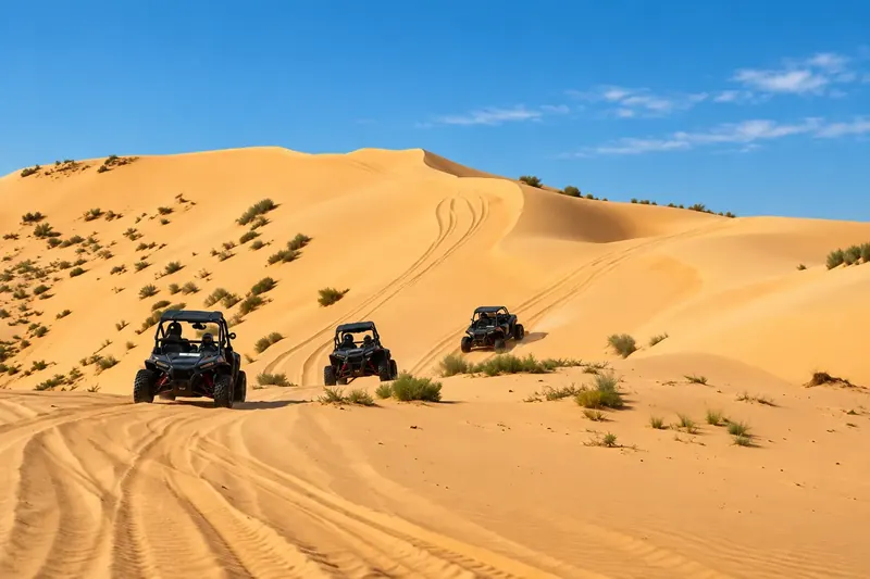 Three Polaris dune buggies driving in line across the Al Khatim dunes near Abu Dhabi