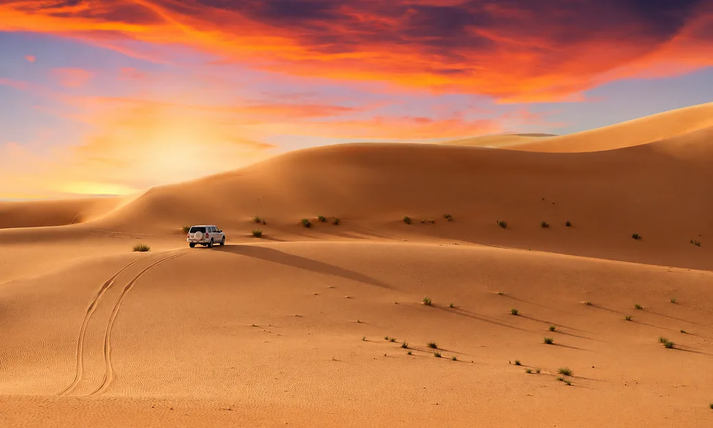 Private 4x4 crossing Abu Dhabi dunes beneath a dramatic evening sky