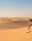 Traveller sandboarding across the Abu Dhabi desert dunes