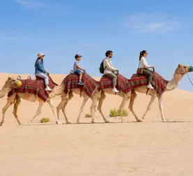 Family taking a guided camel trek in the Abu Dhabi desert