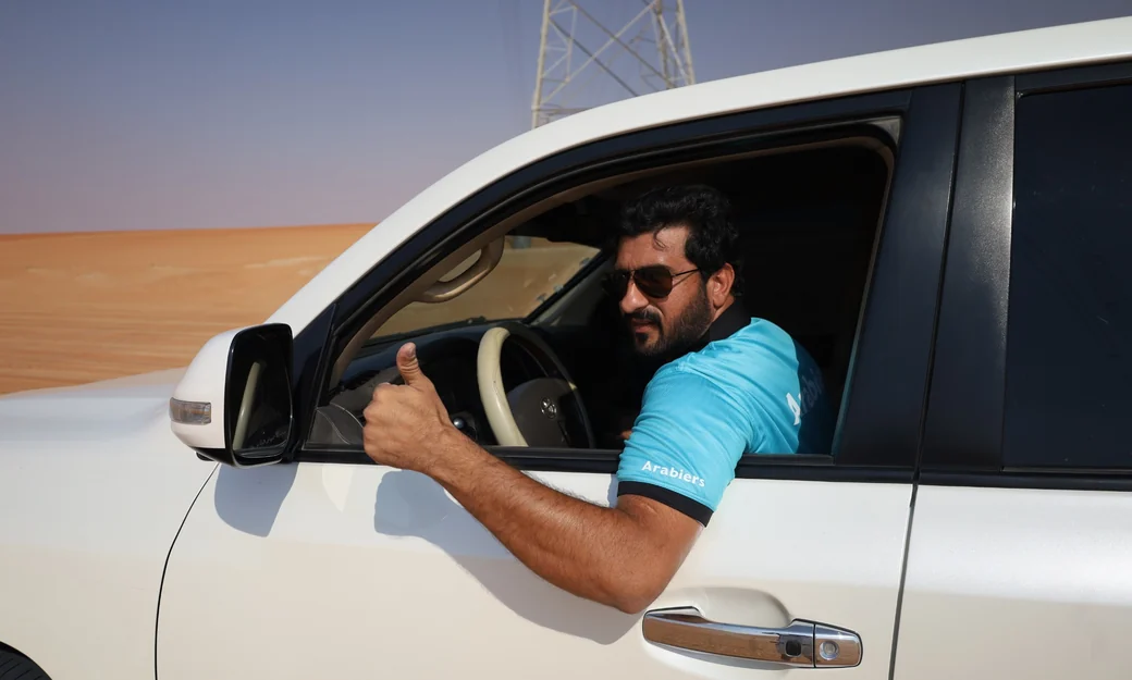 Arabiers Liwa desert guide giving a thumbs up from a Toyota Land Cruiser