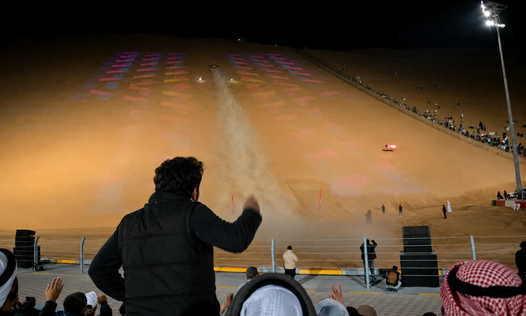 Spectators watching a night-time dune racing event at the Liwa International Festival