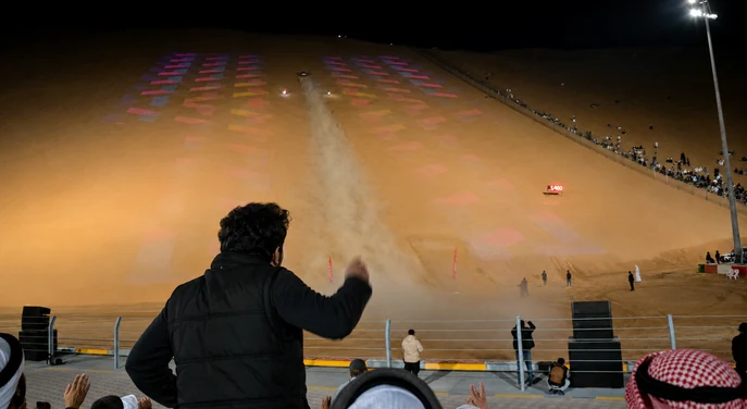 Spectators watching a night-time dune racing event at the Liwa International Festival