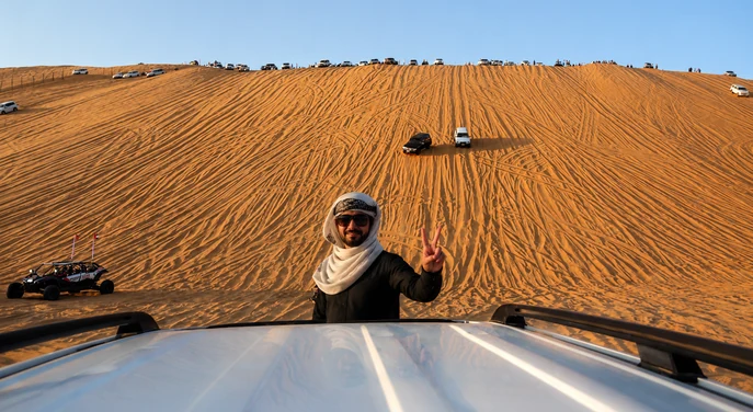 Visitor posing at the base of Tal Moreeb during the Liwa International Festival