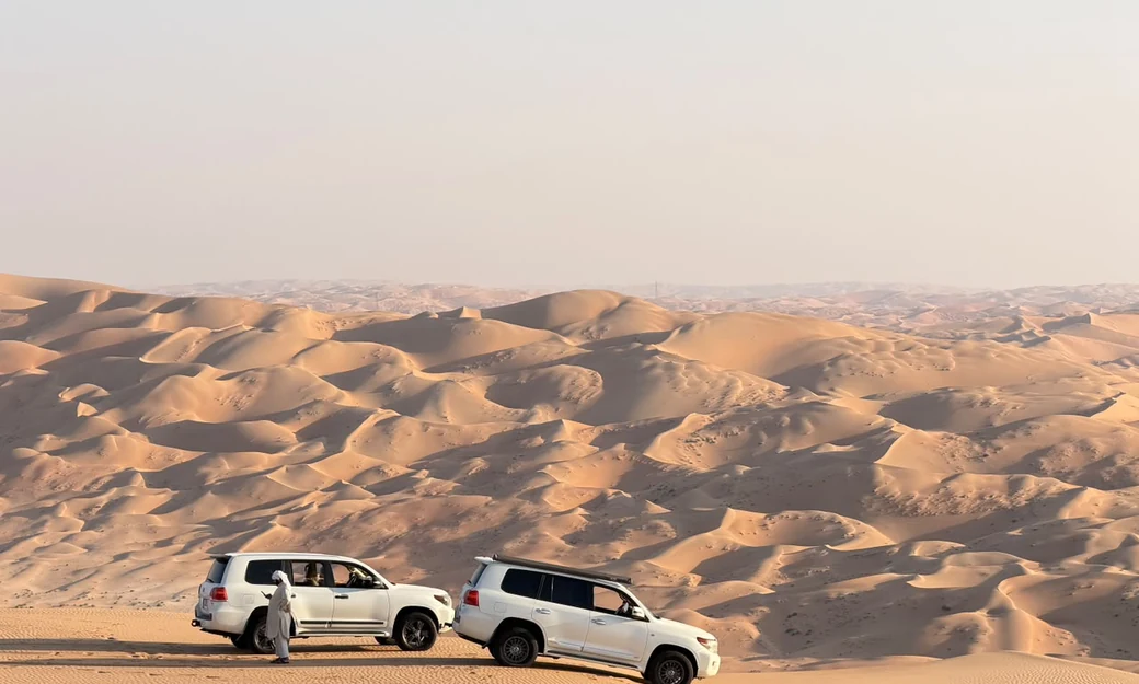 Two Toyota Land Cruisers stopped above the vast Liwa Empty Quarter dunes